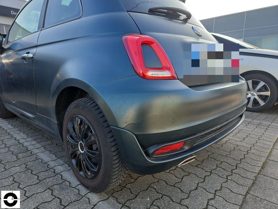 Heckansicht schräg links, dunkelgrauer Kleinwagen, Stoßfänger und Heckbereich sichtbar, keine erkennbaren Schäden