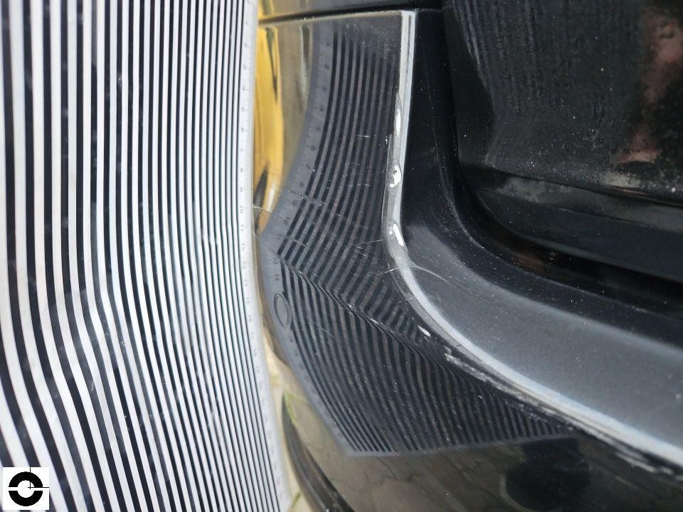 Nahaufnahme Frontbereich, Kratzer an schwarzer Stoßstange mit Maßstab zur Dokumentation