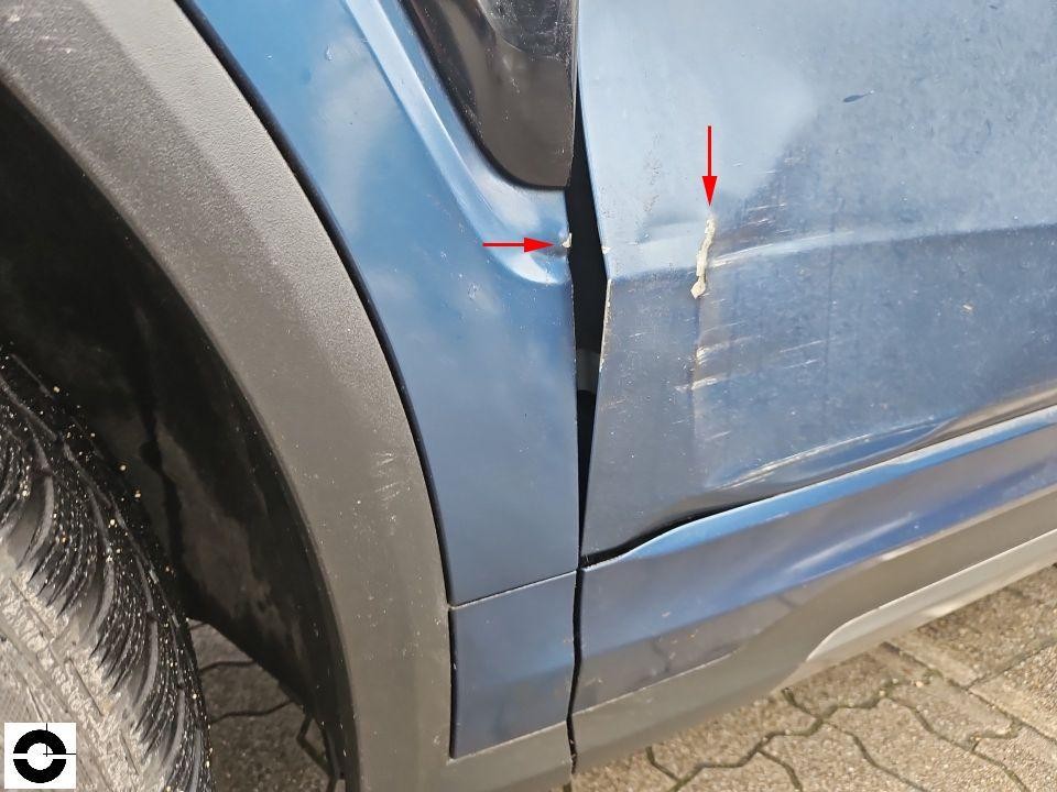 Nahaufnahme Schaden an vorderer linker Tür und Kotflügel, Kratzer und Lackabplatzer mit roten Markierungspfeilen