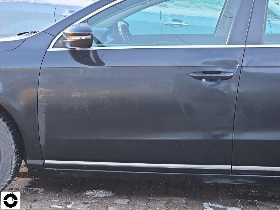 Seitenansicht linke Fahrerseite, vorderer Kotflügel und Tür mit Schmutz und leichten Kratzern